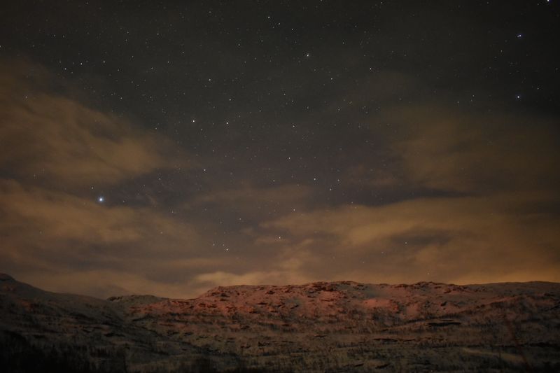 Stars and drifting clouds above snow-covered mountains