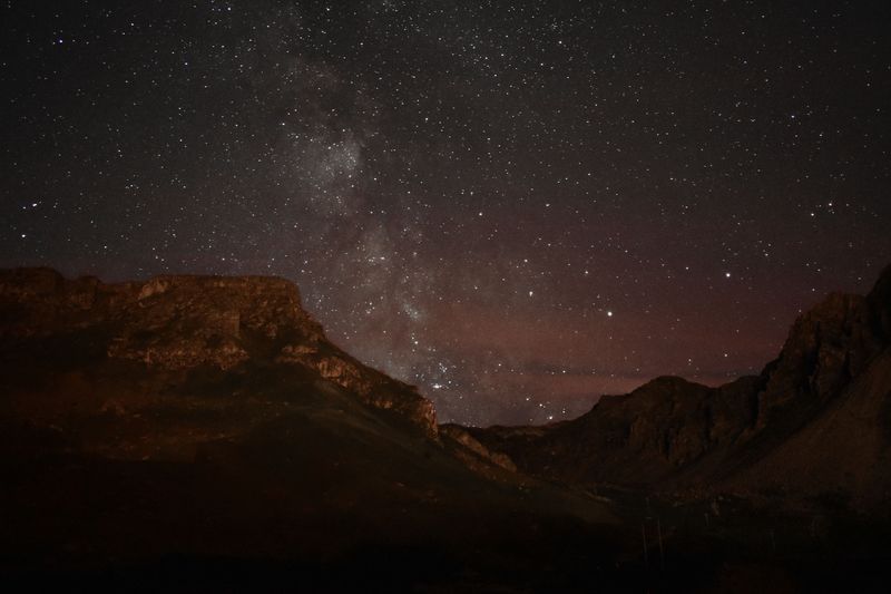 The Milky Way over a dark mountain valley