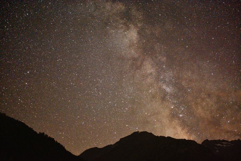 Dense star field and the Milky Way above dark mountain silhouettes